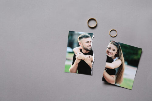 Torn photo of happy couple with rings on grey background. Concept of divorce